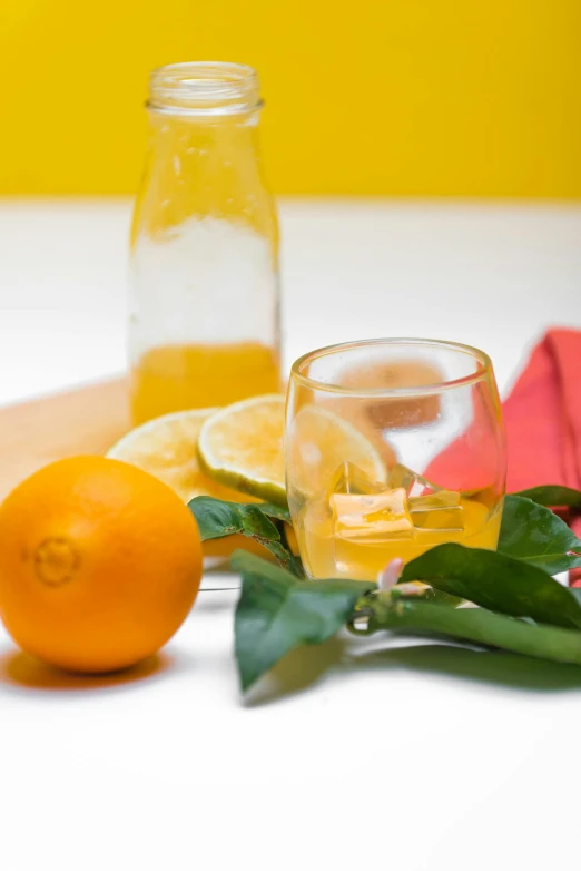 a close up view of a bottle and two glasses near oranges