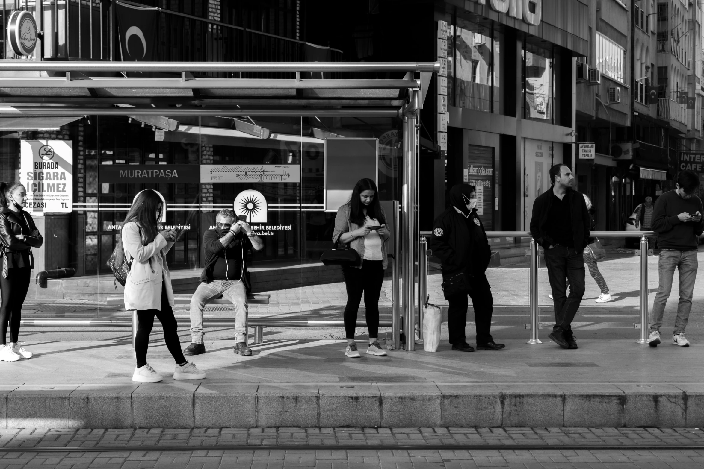 a group of people waiting at a bus stop, by Constantine Andreou, pexels contest winner, music being played, square, white limbo, turkey