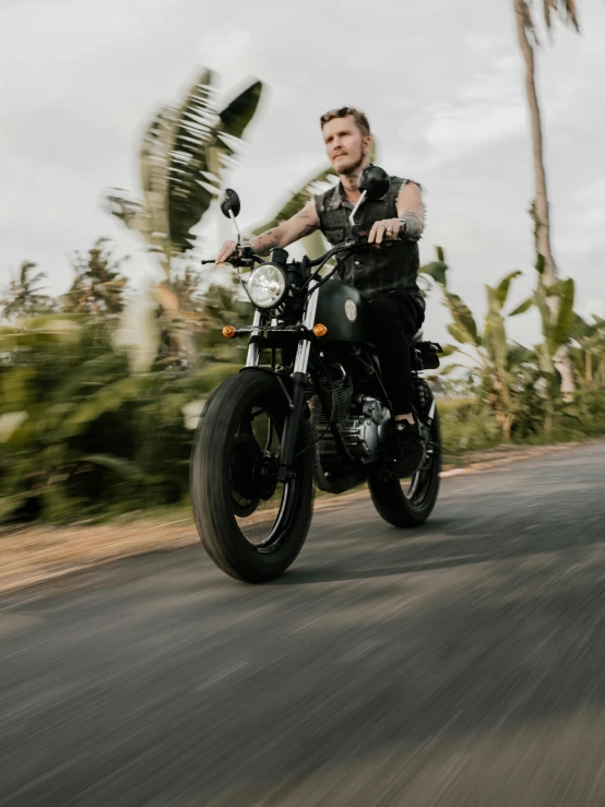 a man riding on the back of a motorcycle down a road, an album cover, by Adam Dario Keel, unsplash, bali, profile image, zoomed in, caspar david