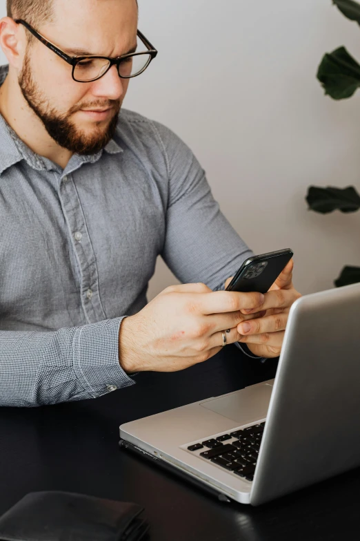 a man sitting at a table with a laptop and cell phone, trending on pexels, corporate phone app icon, holding arms on holsters, grey, caucasian