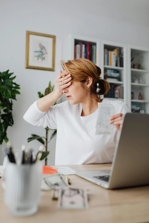 a woman sitting at a desk in front of a laptop, pexels, renaissance, frustrated, showing forehead, instagram post, caucasian