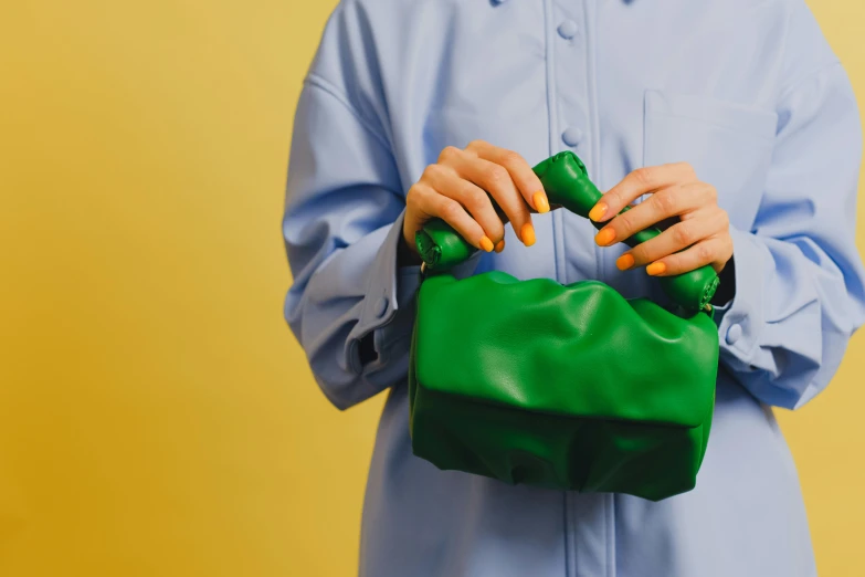 a woman in a blue shirt holding a green purse, by Julia Pishtar, trending on pexels, visual art, future inflatable jacket, healthcare worker, toys, yellow