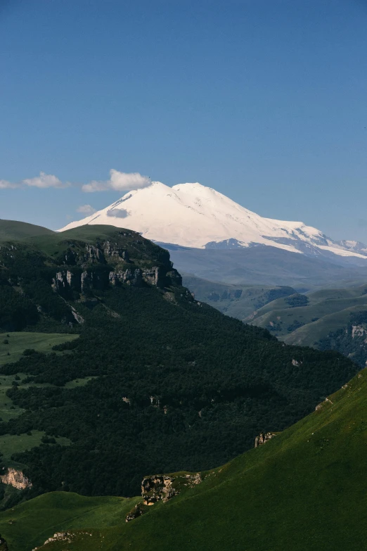 snow capped mountain in the distance, in between rolling hills and a valley