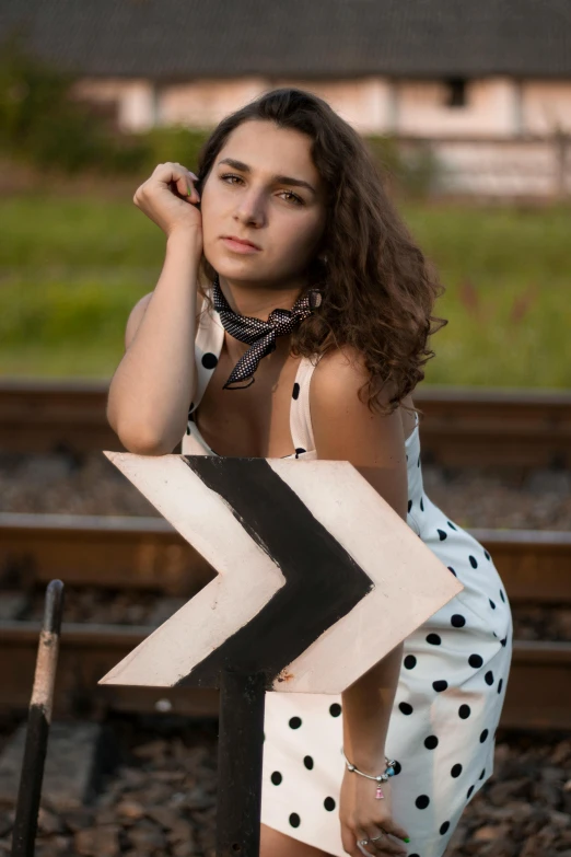 a woman with a chevron look stands near a sign