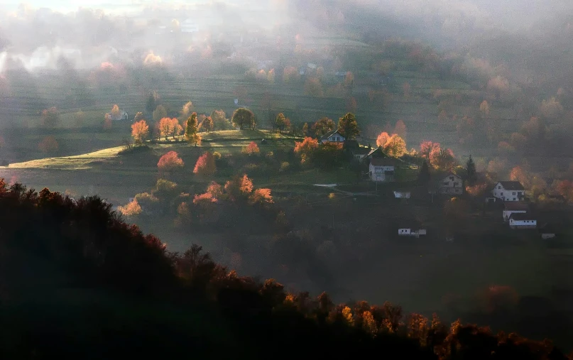 a foggy landscape in autumn, showing houses and mountains