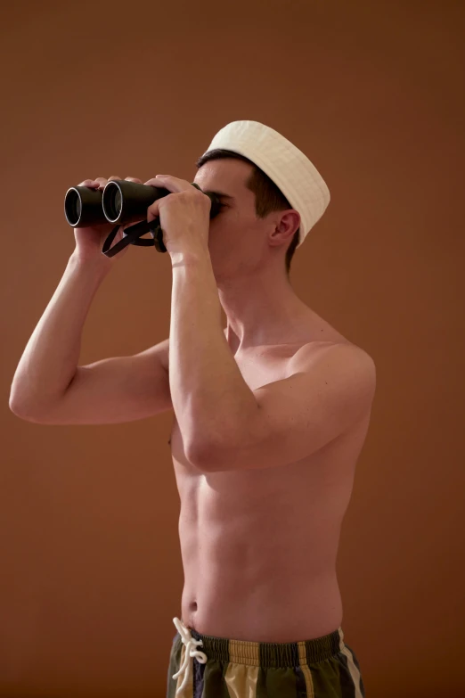 a shirtless man looking through a pair of binoculars, by Alison Geissler, wearing a white bathing cap, non binary model, arabian, ignant