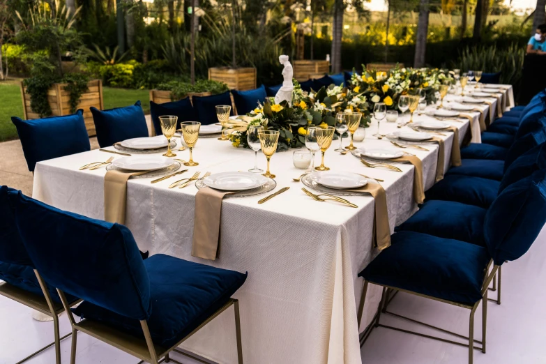 an outdoor dining table set with dinnerware and flowers