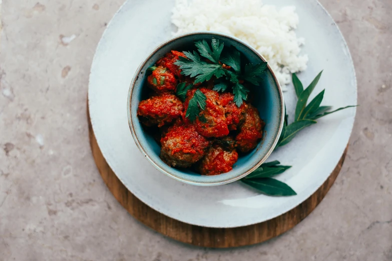 a bowl of meatballs and rice on a plate, by Emma Andijewska, unsplash, green and red plants, textured, paprika, blue