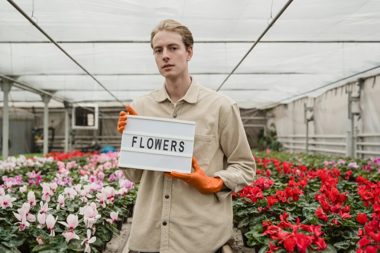 a man standing in a greenhouse holding a sign, pexels contest winner, renaissance, the platonic ideal of flowers, lachlan bailey, offwhite, (flowers)