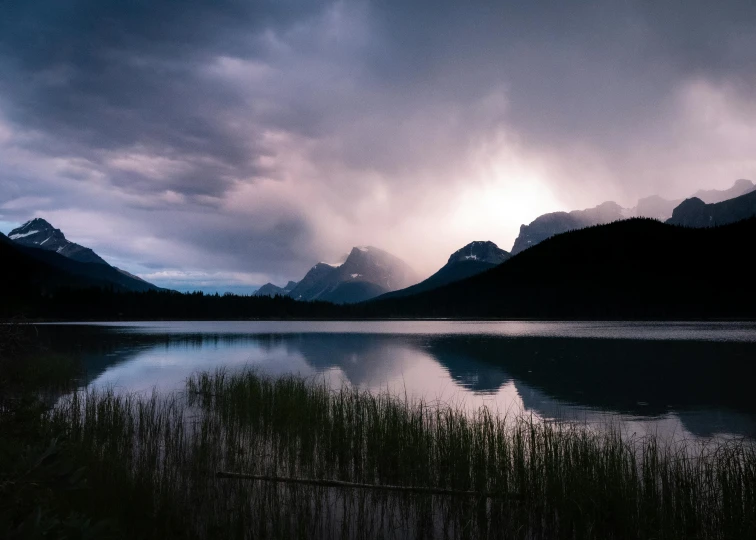 a view of clouds over the mountains and water