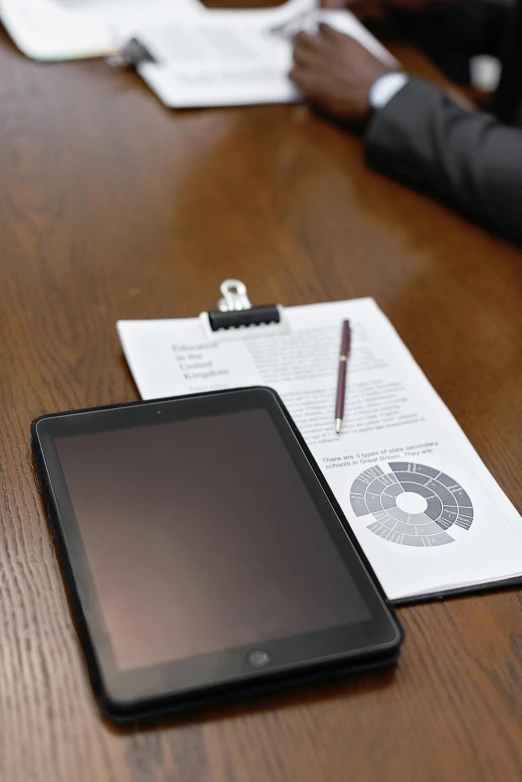 a tablet computer sitting on top of a wooden table, private press, holding a clipboard, thumbnail, multiple stories, up close