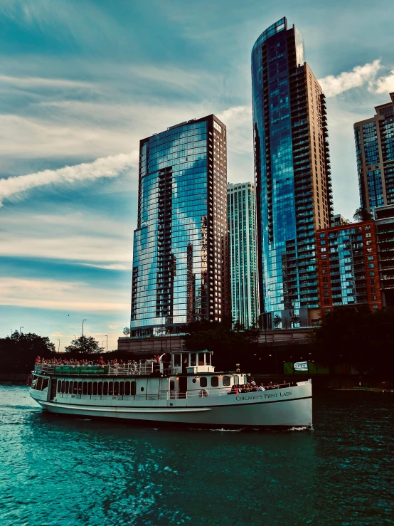 a white boat floating across a river next to tall buildings