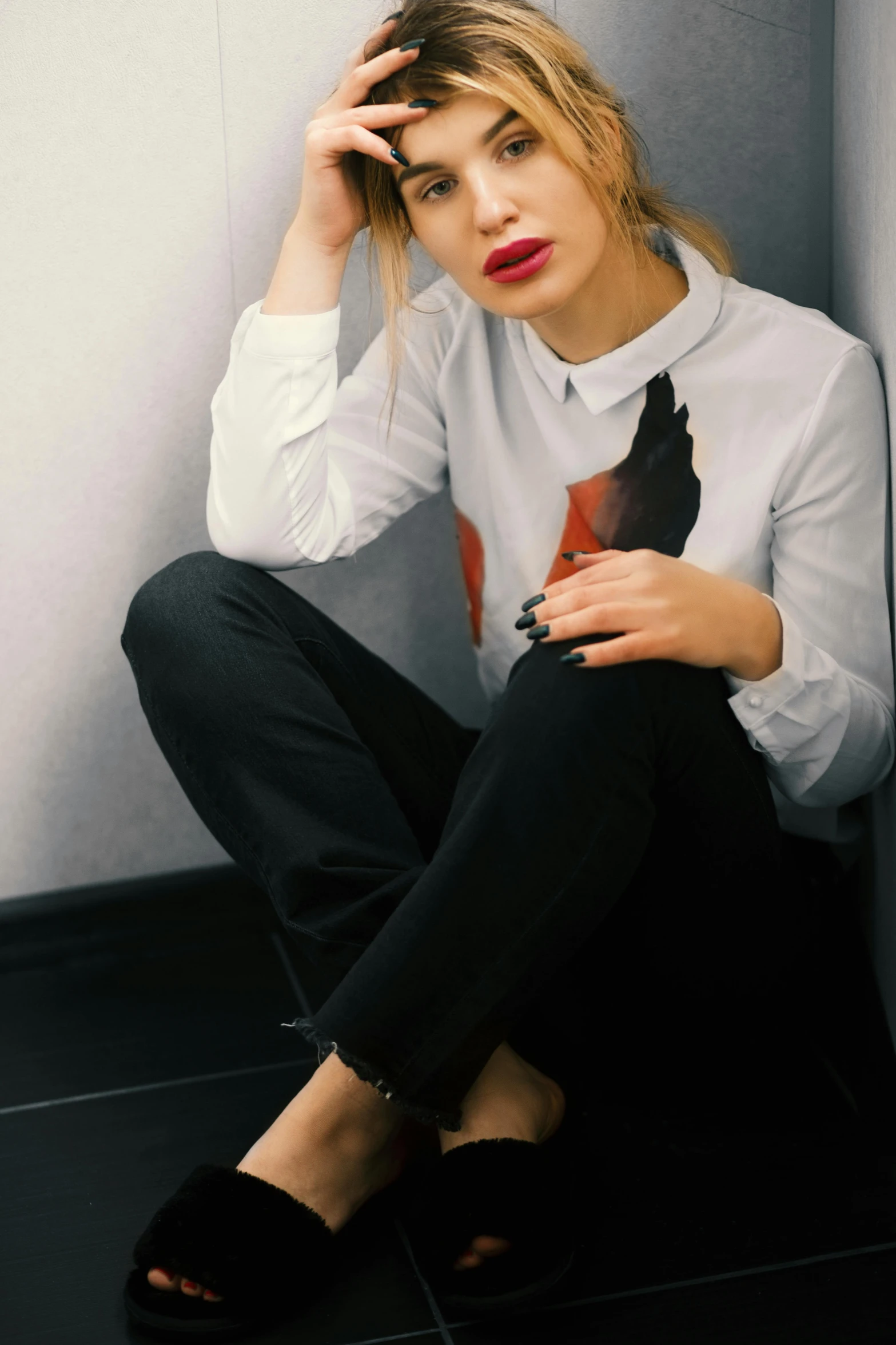 a woman sitting on the floor with her hand on her head, inspired by Ksenia Milicevic, trending on pexels, antipodeans, shirt, red lips, black trousers, foxes