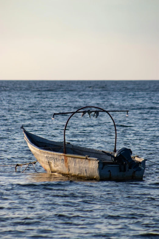 a small boat floating on top of a body of water, near the sea, fishing pole, rusted junk, afar