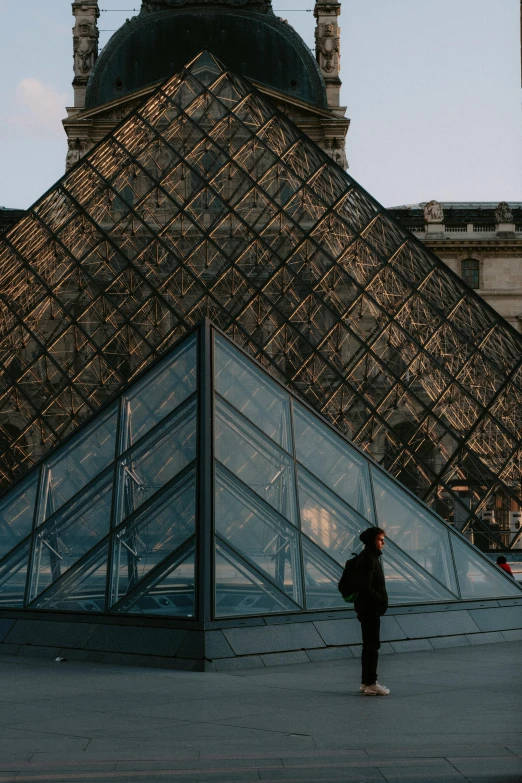 a person standing in front of a glass pyramid, a photo, by Julia Pishtar, trending on unsplash, ornate french architecture, taken in the late 2010s, cinematic lut, brown