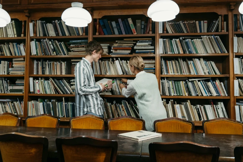 a couple of people standing in front of a bookshelf, unsplash, academic art, digging, lachlan bailey, government archive photograph, mid morning lighting