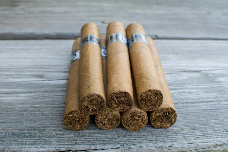 a bunch of cigars sitting on top of a wooden table, silver mist, 6 pack, medium-shot, single