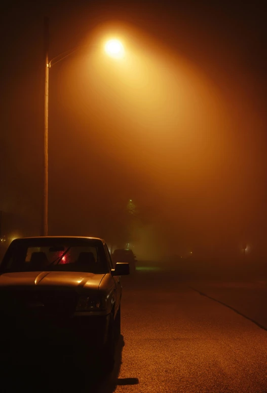 a red stop light shining in the fog on a street