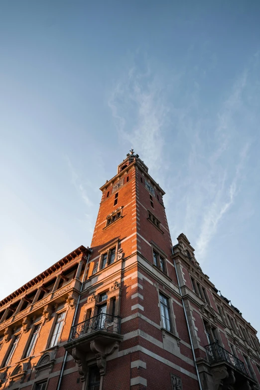 a tall brick building with a clock tower, unsplash, art nouveau, late summer evening, aardman studios, view from bottom to top, thumbnail