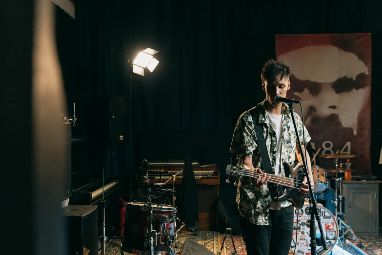 a man that is playing a guitar in a room, an album cover, unsplash, standing straight, syd, band playing, tv still