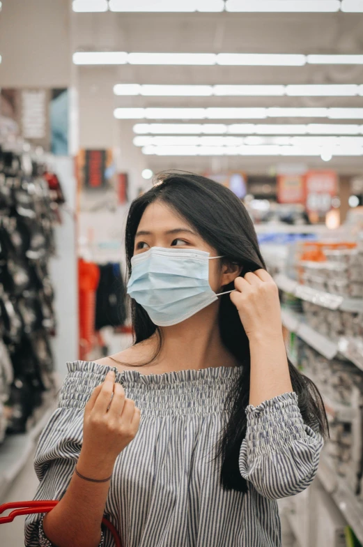 a woman wearing a surgical mask standing in a store aisle