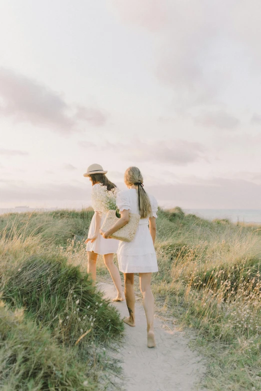 two young women walking down a path on the grass