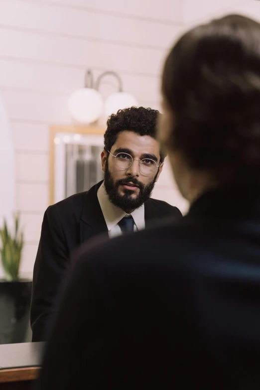 man in suit with serious expression sitting by desk