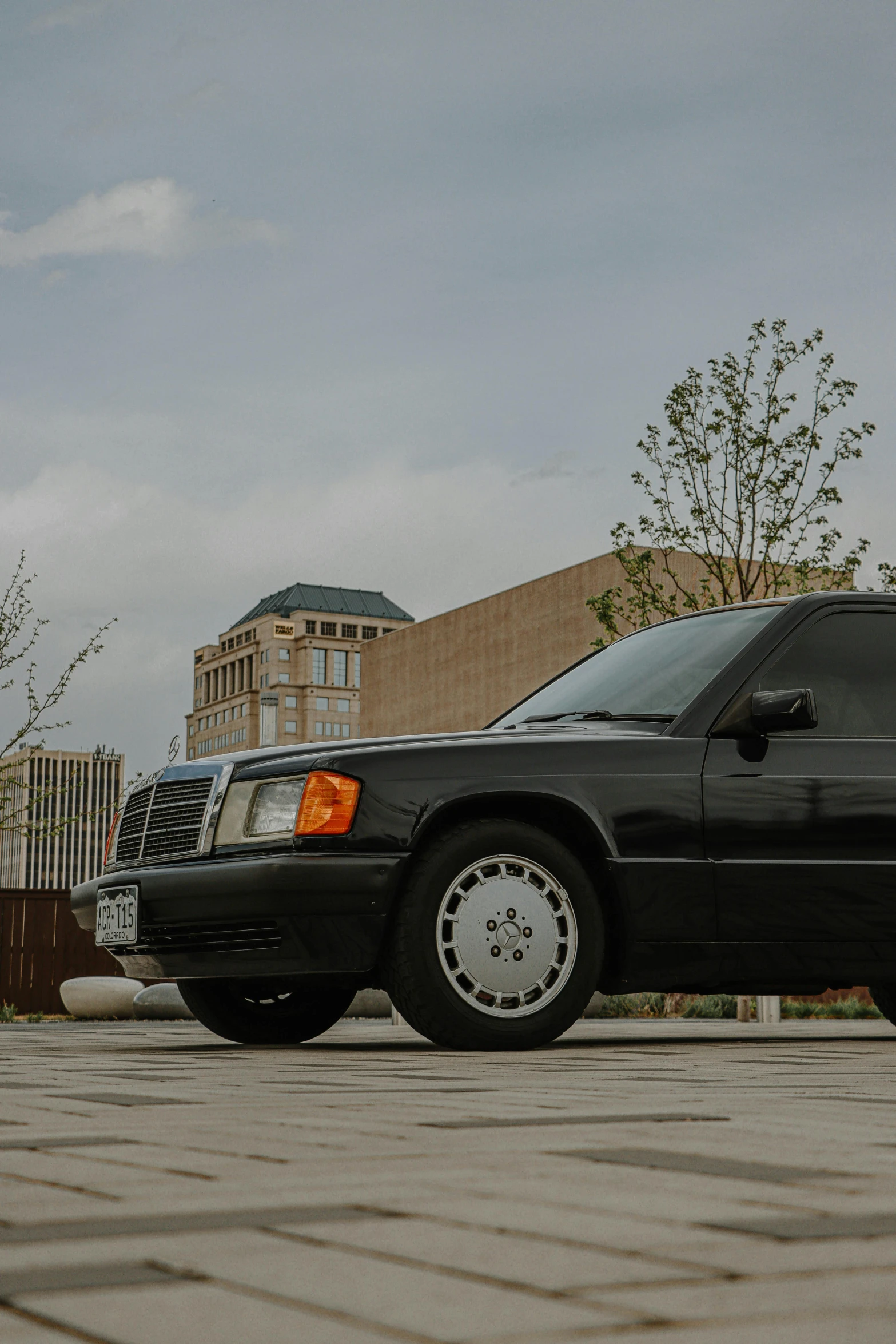 a black car is parked in a parking lot, an album cover, unsplash, photorealism, mercedez benz, 1990 photograph, panorama shot, historical photo