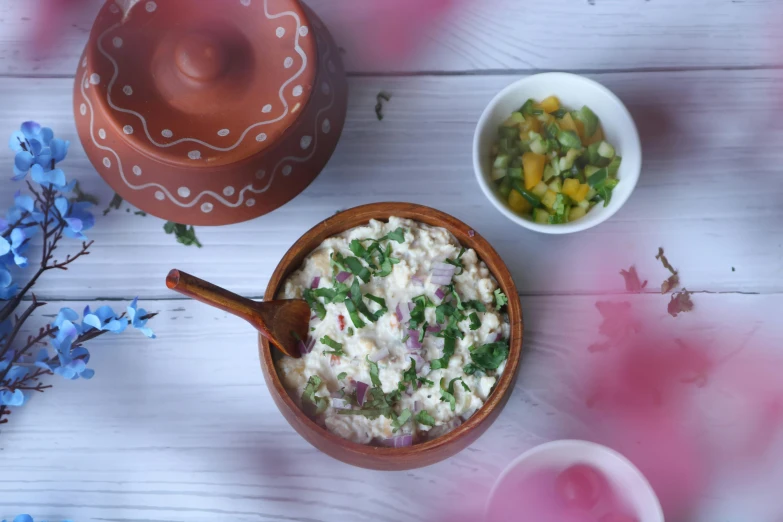 a bowl of food sitting on top of a wooden table, a picture, mayo, herbs and flowers, background image, salsa vendor