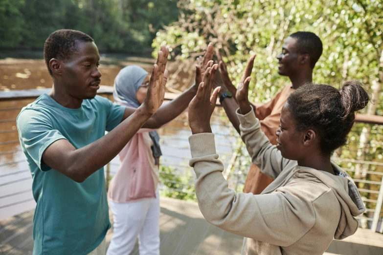 a group of people giving each other a high five, by Arabella Rankin, hurufiyya, live-action adaptation, nuri iyem, close - up photograph, a park