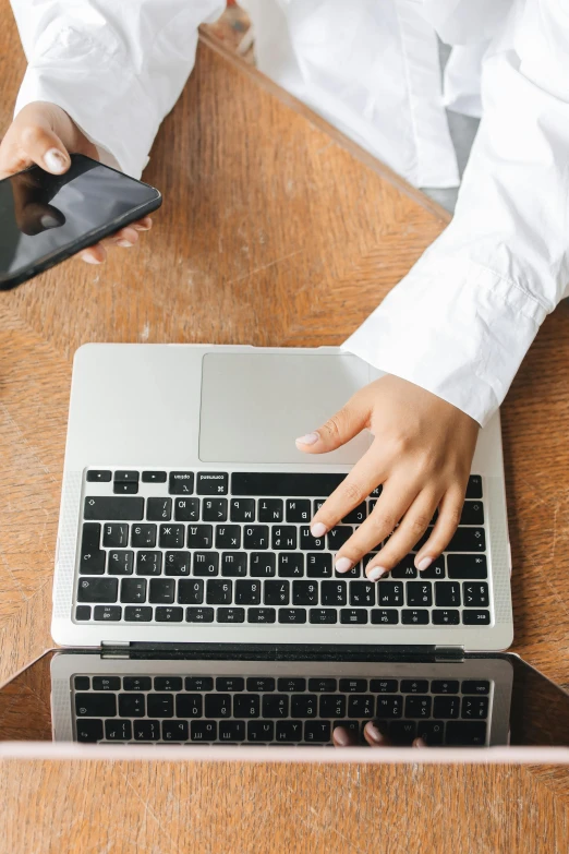 a person sitting at a table with a laptop and cell phone, 9 9 designs, zoomed in, keyboard, thumbnail