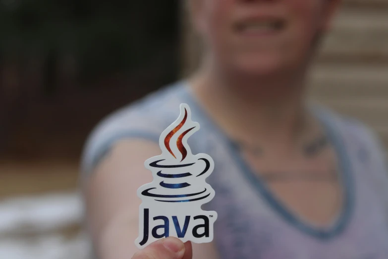 a woman holding up a sticker with the word java on it, unsplash, steam workshop, full colour, medium close shot, summer evening