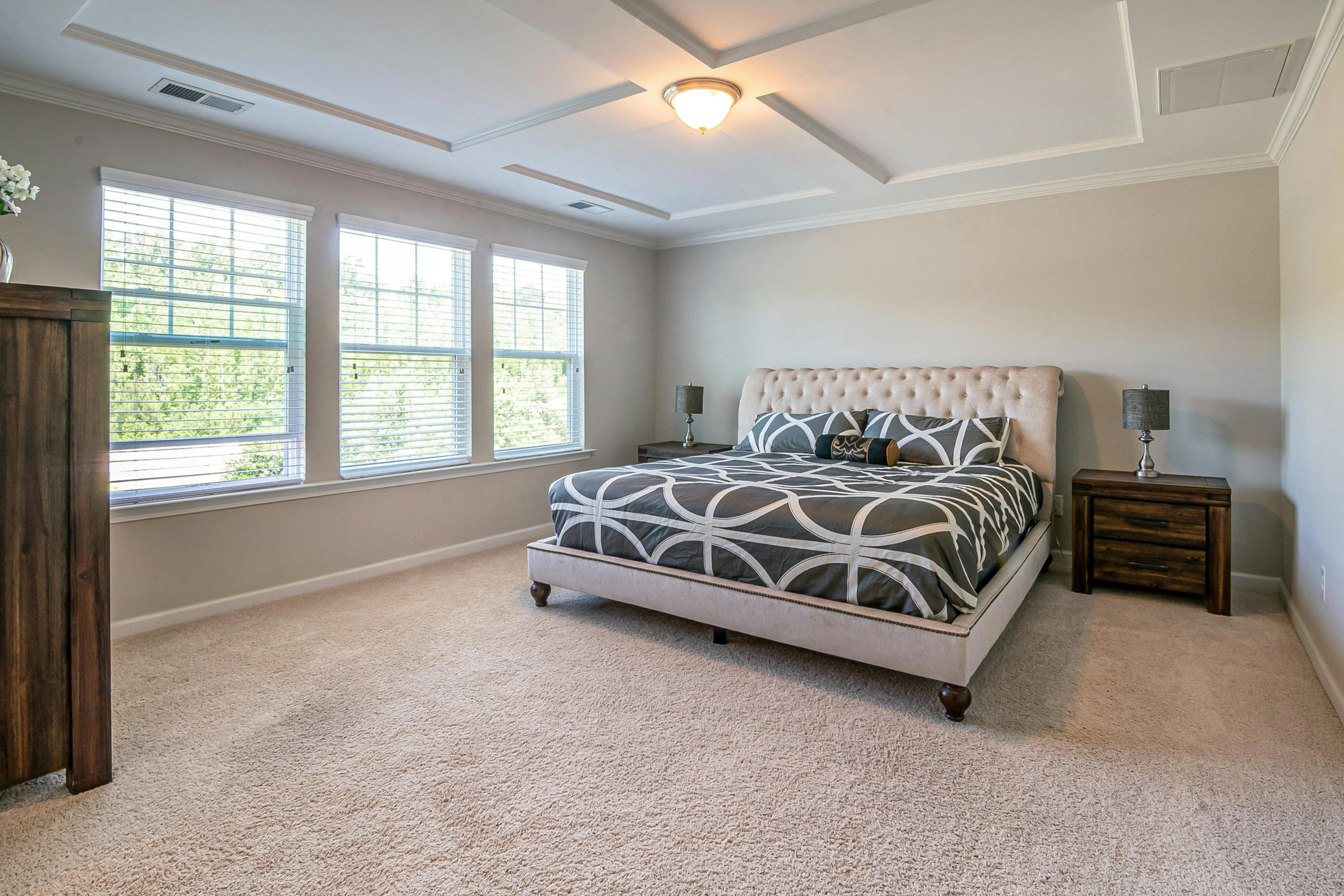 a large master bedroom with carpet and lighting