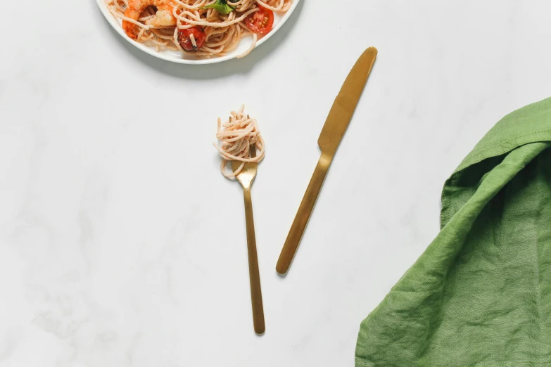 a close up of a plate of food on a table, inspired by Charles Roka, minimalism, holding magical kitchen knives, gold, spaghetti, made in gold