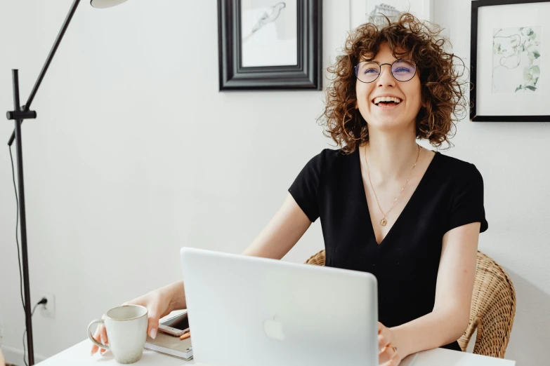 a woman sitting at a table with a laptop, curly haired, giddy smirk, sanja stikovic, avatar image