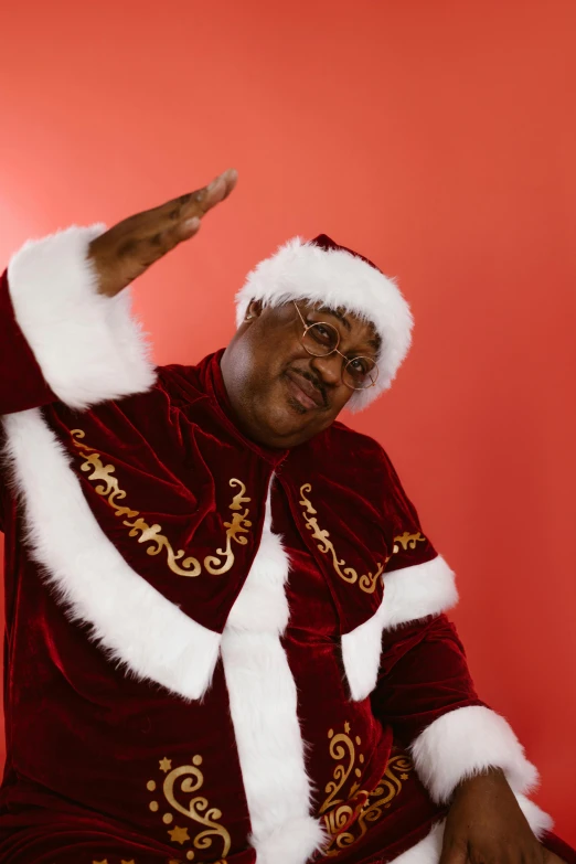 a man in a santa suit points to soing on a red background