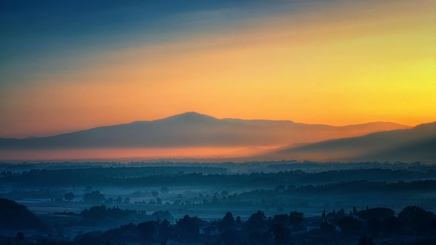 the sun is setting over a valley with mountains in the distance, by Adam Marczyński, pexels contest winner, sumatraism, colorful haze, the city of santa barbara, cyan and orange, soft mist