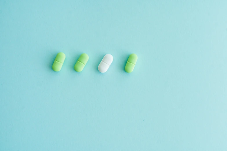 green and white pills on a blue background, by Emma Andijewska, unsplash, antipodeans, 🎨🖌️, three colors, lined up horizontally, knee