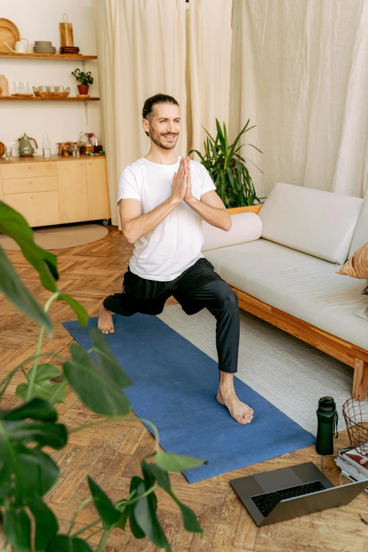 a man practices yoga on a rug in the living room