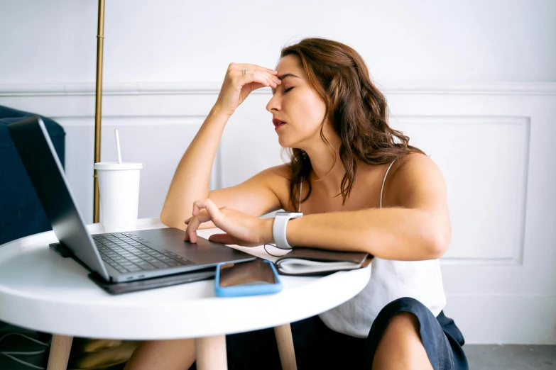 a woman sitting at a table with a laptop, trending on pexels, happening, muscular and exhausted woman, sleepy fashion model face, thumbnail