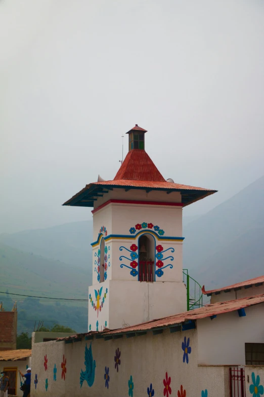 a white building with a red roof and a clock tower, inspired by Carlos Enríquez Gómez, quito school, mexican mustache, uttarakhand, chimneys, multicolor