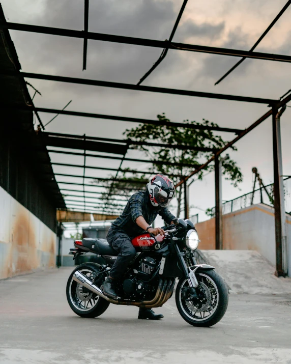 a man riding on the back of a motorcycle, pexels contest winner, renaissance, in front of a garage, motorcycle helmet, black and red scheme, cafe racer