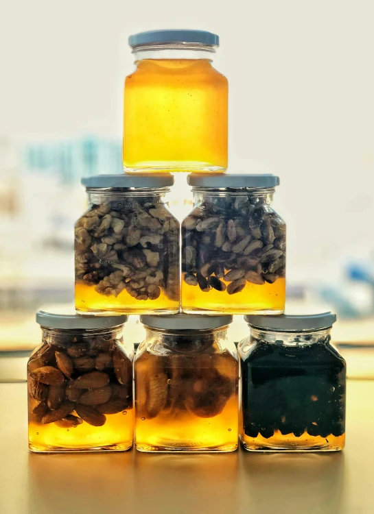 a stack of jars filled with coffee beans, bioluminescent hypercubes, honey and bee hive, 6 pack, dubai