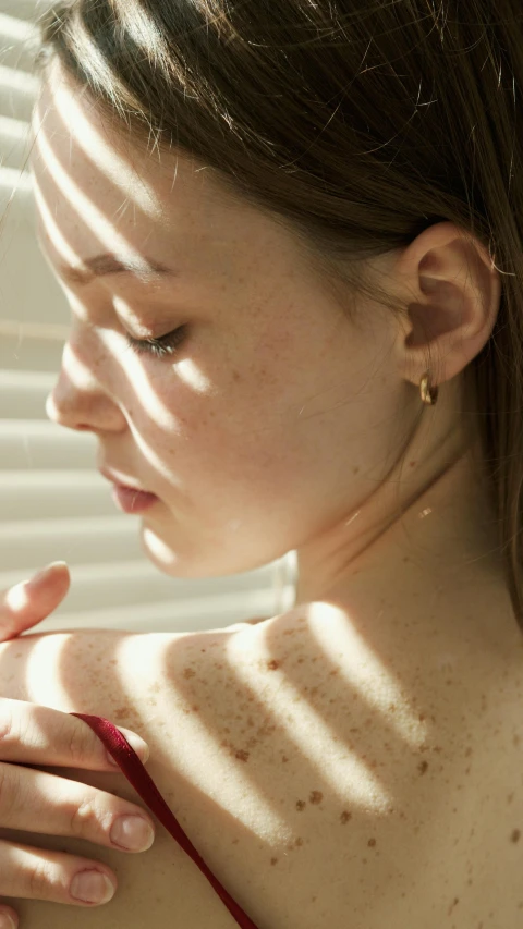 a close up of a person holding a cell phone, an album cover, inspired by Elsa Bleda, photorealism, gold earring, sunbathed skin, soft shadow, thoughtful