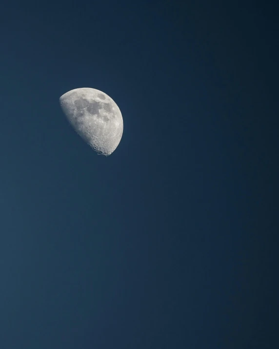 a full moon seen in the blue sky on a clear day