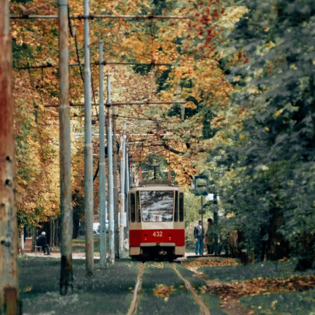 a red and white train traveling down train tracks, by Maksimilijan Vanka, pexels contest winner, socialist realism, grassy autumn park outdoor, street tram, ektachrome color photograph, gif