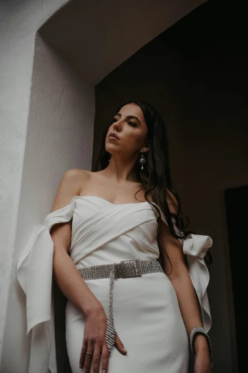 a woman in a white dress leaning against a wall, inspired by Gina Pellón, pexels contest winner, dramatic lighting from above, middle eastern, formal wear, balcony