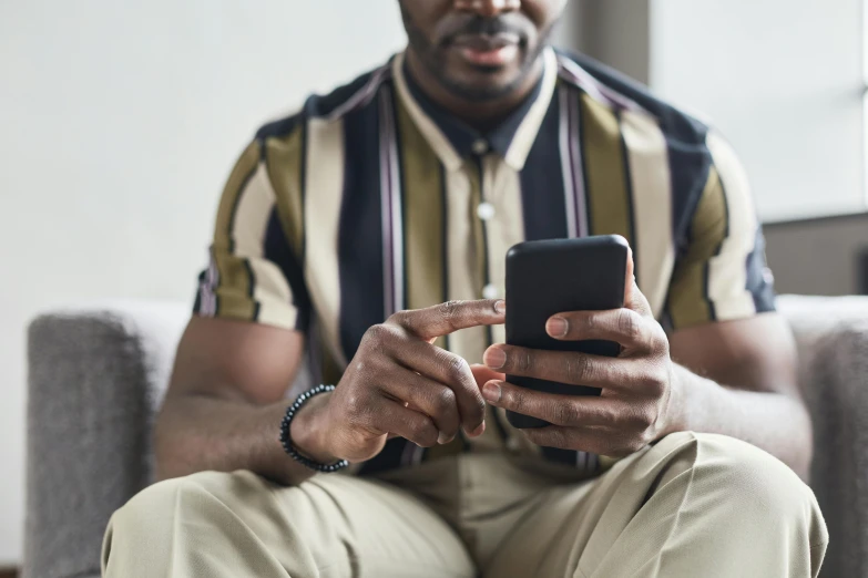 a man sitting on a couch using a cell phone, trending on pexels, renaissance, wearing stripe shirt, man is with black skin, sitting on man's fingertip, in front of the internet