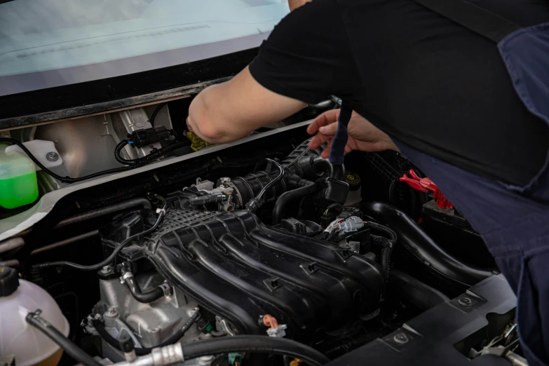 a man is working on a car engine, by Joe Bowler, unsplash, in a modified nissan skyline r34, alana fletcher, wiring, soft and detailed