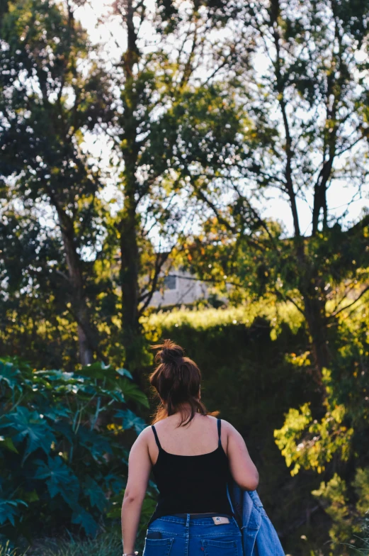 a woman walking down a dirt road carrying a blue jacket, unsplash, house on a hill, in a verdant garden, late afternoon sun, manuka